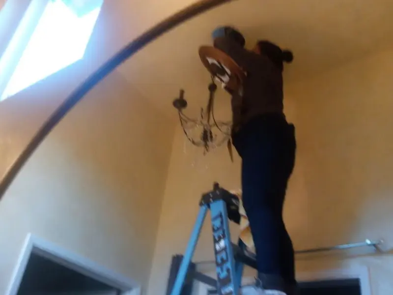 Electrician installing a chandelier in a Wedgefield residence